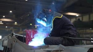Worker wearing a protective helmet while welding a metal component