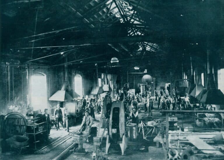 Historic workshop with workers and industrial machinery