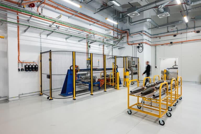 Bright production hall with fenced machinery and yellow handling equipment